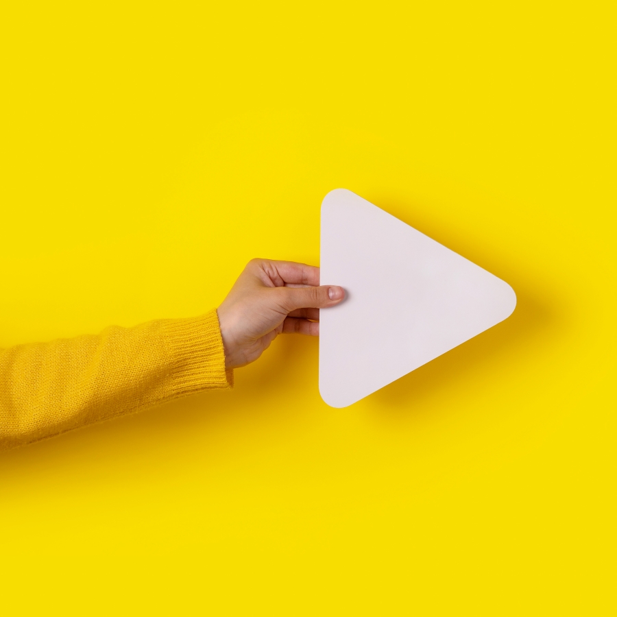 Hand hält Symbol für Mediaplayer-Schaltfläche vor trendigem gelbem Hintergrund, Panorama-Layout